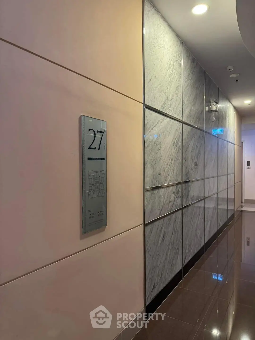 Modern elevator lobby with sleek marble walls and polished floors on the 27th floor.