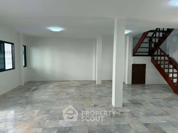 Spacious open-plan living area with modern staircase and tiled flooring