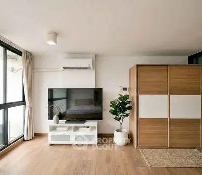 Modern living room with large TV, wooden flooring, and stylish decor