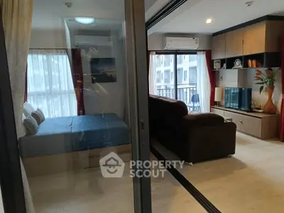 Modern apartment interior with open living room and bedroom, featuring stylish furniture and natural light.