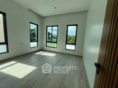 Spacious sunlit room with large windows and modern flooring, perfect for a serene living space.