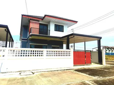 Modern two-story house with red accents and spacious driveway in suburban neighborhood.
