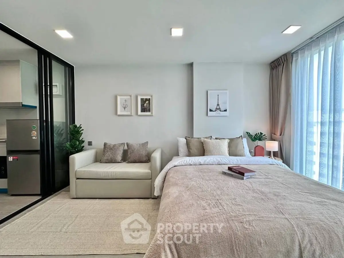 Modern studio apartment with cozy bed and stylish decor, featuring a compact kitchen area.