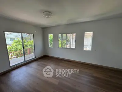 Spacious empty room with large windows and wooden flooring, perfect for customization.