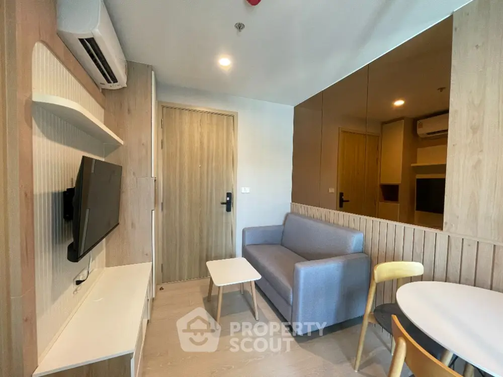 Modern living room with sleek design, featuring a cozy sofa, wall-mounted TV, and stylish decor.
