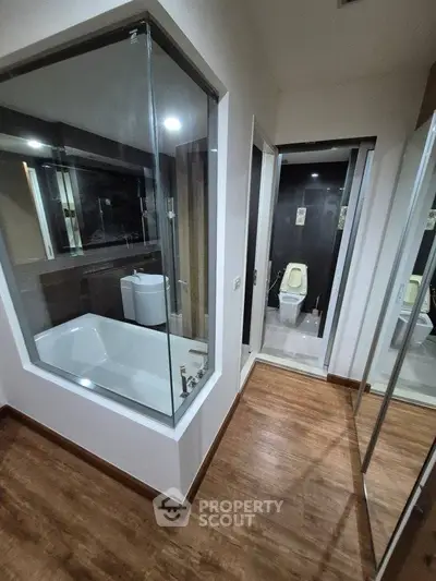 Modern bathroom with glass-enclosed bathtub and wooden flooring