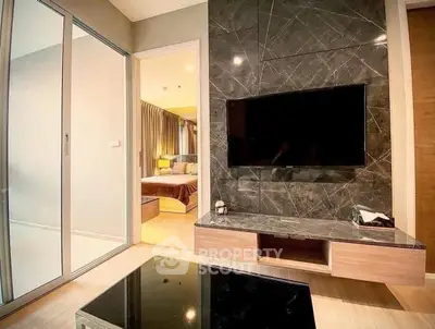 Modern living room with sleek TV setup and view into cozy bedroom