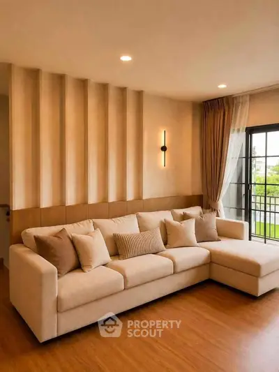 Elegant living room with modern beige sofa and stylish wall decor, featuring large windows for natural light.