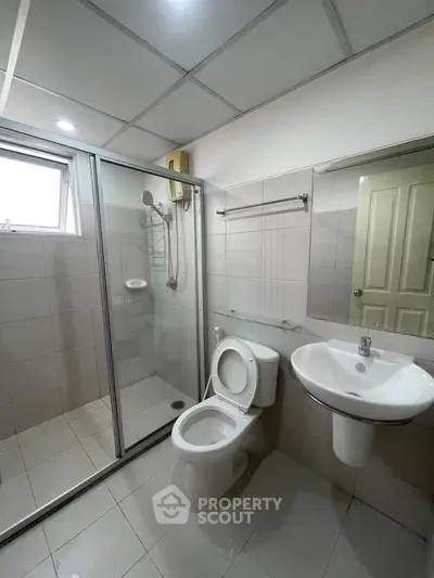 Modern bathroom with glass shower, sleek fixtures, and neutral tiles.