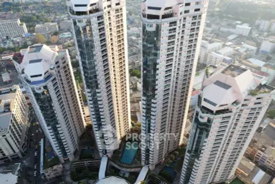 Stunning aerial view of modern high-rise residential towers with cityscape backdrop, showcasing urban living at its finest.