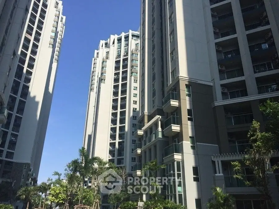 Modern high-rise residential buildings with lush greenery and clear blue sky.