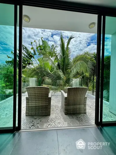 Luxurious balcony with tropical garden view and stylish wicker chairs