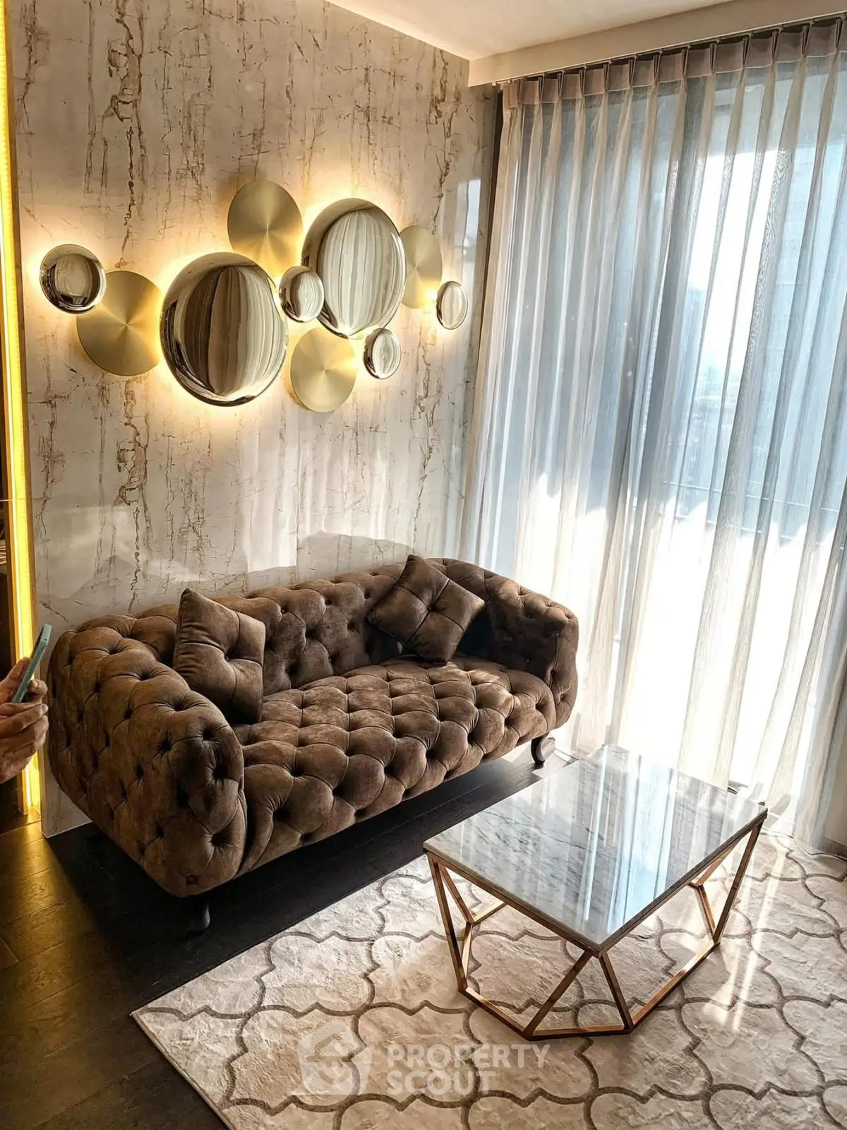 Luxurious living room with plush sofa, elegant mirrors, and natural light through sheer curtains.