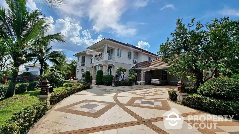 Luxurious villa with spacious driveway and lush garden under blue sky