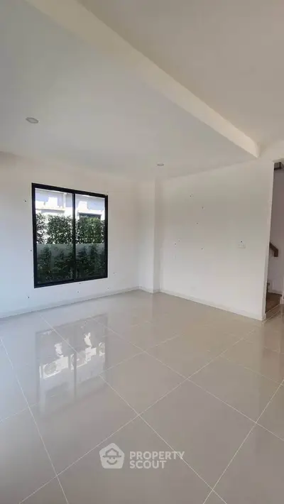 Spacious empty room with large window and glossy tiled floor