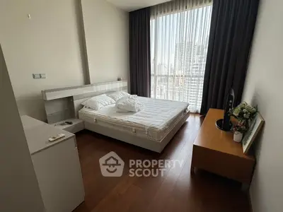 Modern bedroom with city view, featuring sleek furniture and floor-to-ceiling windows.