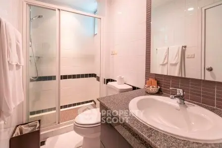 Modern bathroom with glass shower and sleek countertop in stylish apartment.