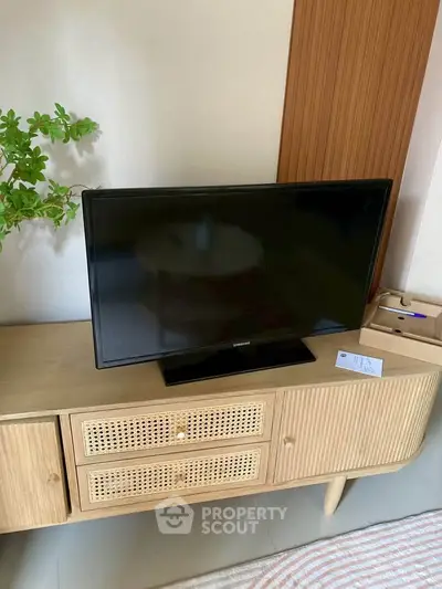 Stylish living room with modern TV on a chic wooden console, perfect for cozy home entertainment.