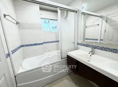 Modern bathroom with bathtub and sleek vanity in a bright, tiled space.