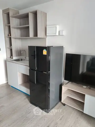 Modern apartment kitchen with sleek black fridge and stylish shelving