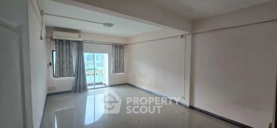 Spacious empty room with large window and air conditioning, ideal for customization.