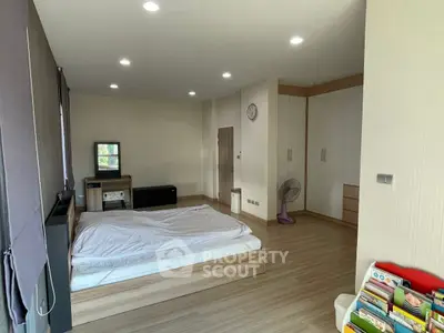 Spacious bedroom with modern design and ample natural light, featuring wooden flooring and built-in storage.