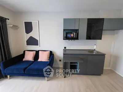 Modern studio apartment with sleek kitchenette and cozy blue sofa, perfect for urban living.