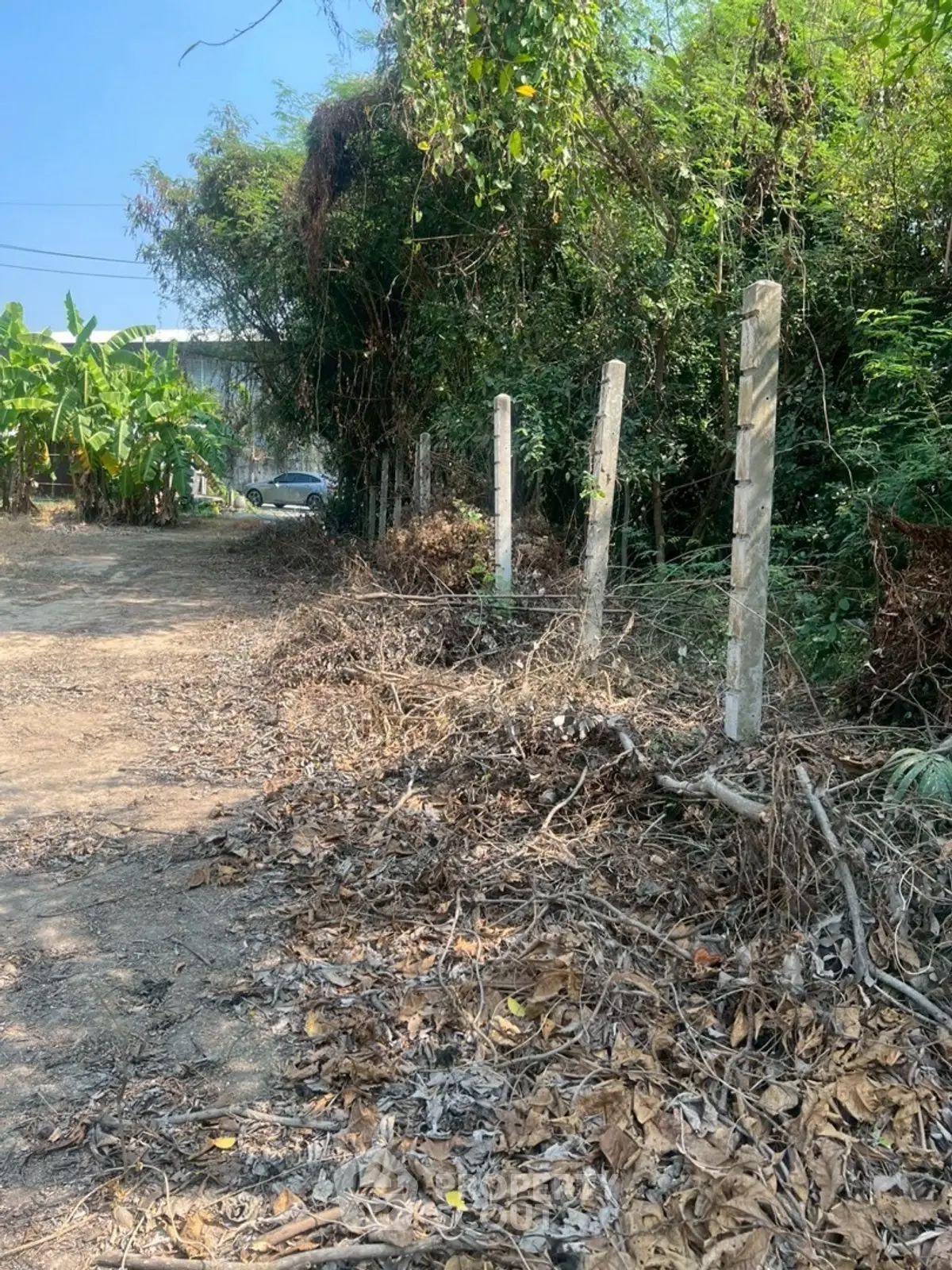 Vacant land with potential for development, surrounded by lush greenery and a rustic fence.