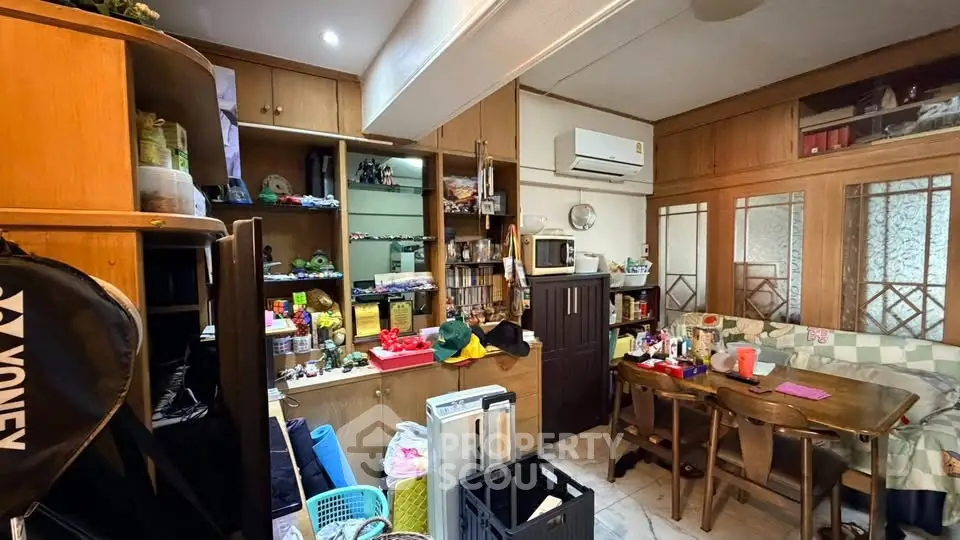 Cozy living room with wooden cabinets and dining area, featuring air conditioning and ample storage.