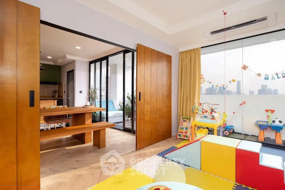 Spacious family-friendly living room with play area and city view balcony
