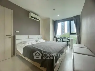 Modern bedroom with large window and city view, featuring sleek furniture and neutral tones.