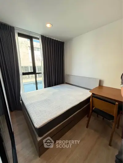 Modern bedroom with large window and stylish furnishings in a contemporary apartment.