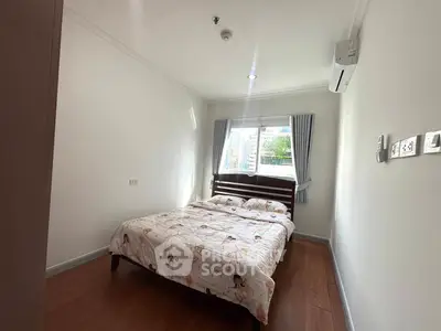 Cozy bedroom with natural light and air conditioning, featuring a comfortable bed and wooden flooring.