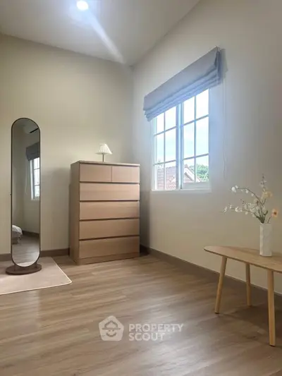 Bright bedroom with modern wooden furniture and large window view.