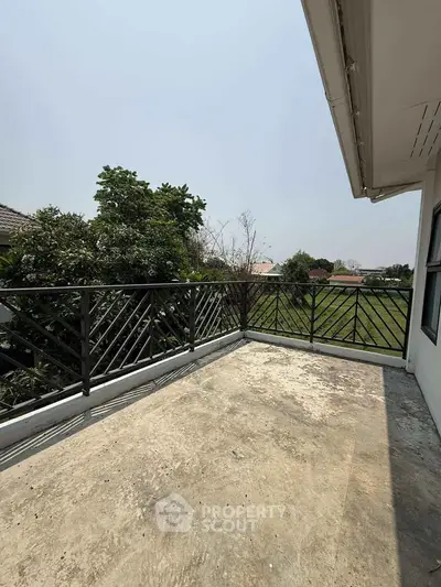 Spacious balcony with scenic view of greenery and clear sky, perfect for relaxation.