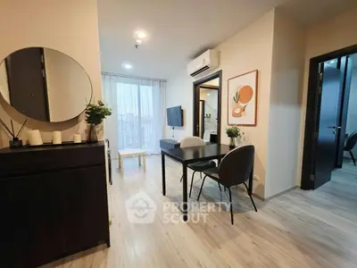 Modern living room with stylish decor and natural light, featuring a dining area and wall-mounted TV.