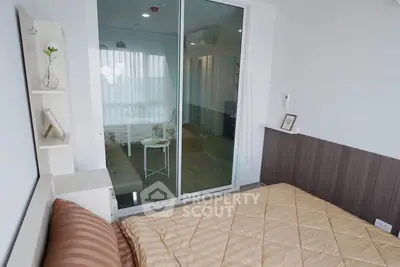 Modern bedroom with cozy decor and sliding glass doors leading to a bright living area.