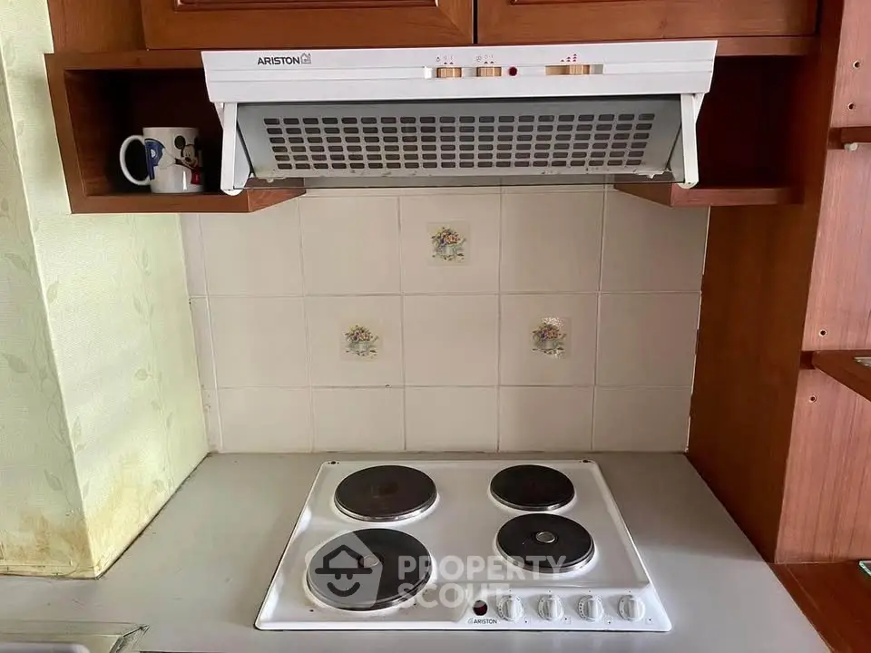 Compact kitchen with electric stove and overhead exhaust fan