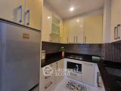 Modern kitchen with sleek cabinetry and built-in appliances in a cozy apartment.