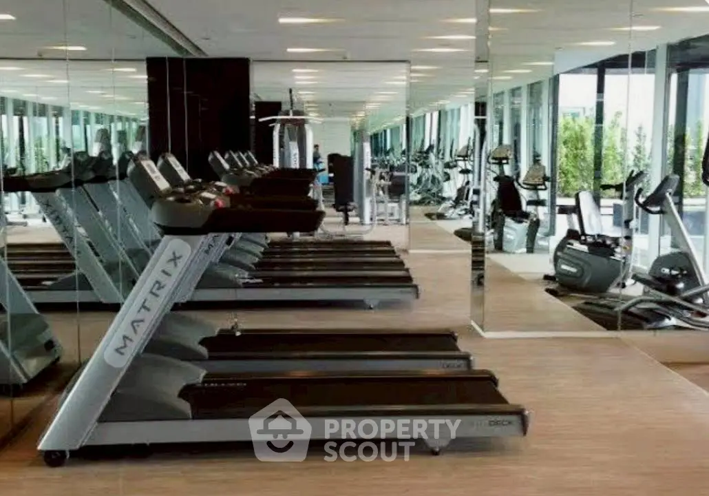 Modern gym with state-of-the-art equipment and mirrored walls in luxury residential building.