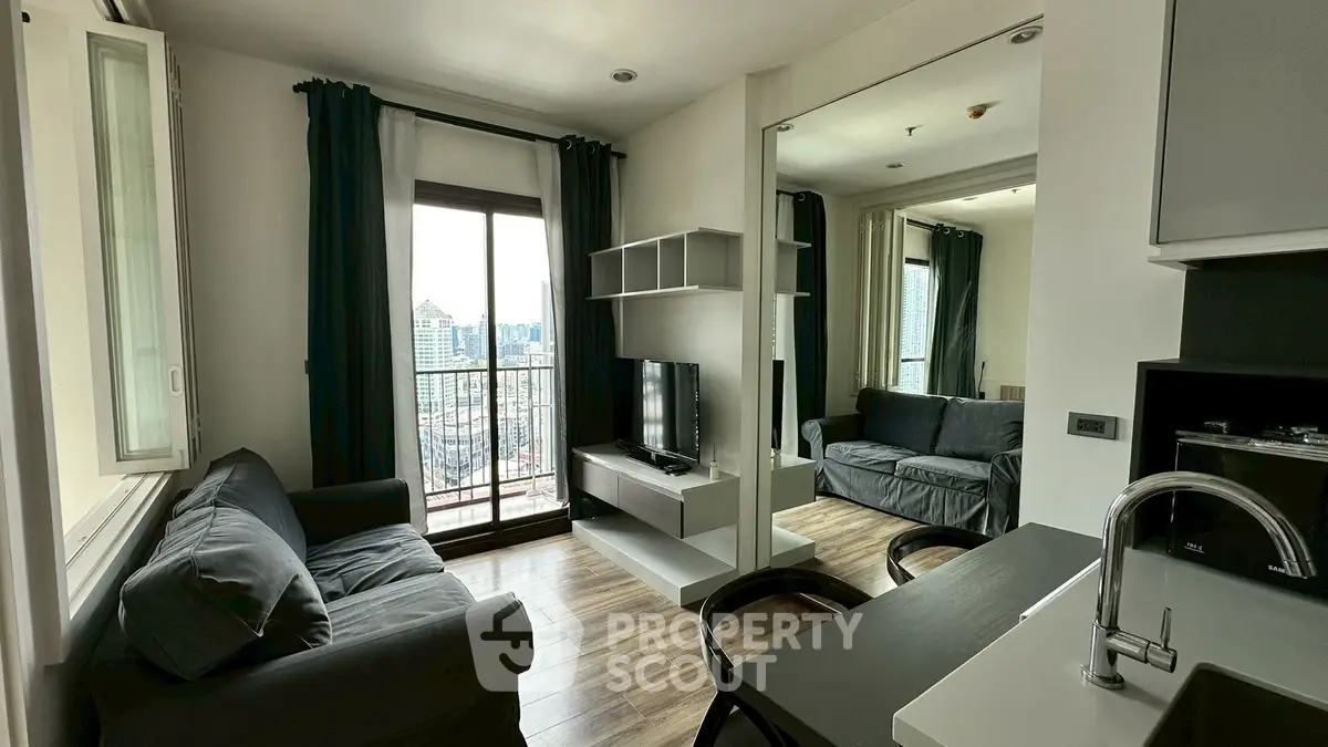 Modern living room with balcony and city view, featuring sleek furniture and open layout.