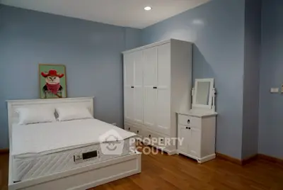 Charming bedroom with white furniture and wooden flooring, perfect for cozy living.