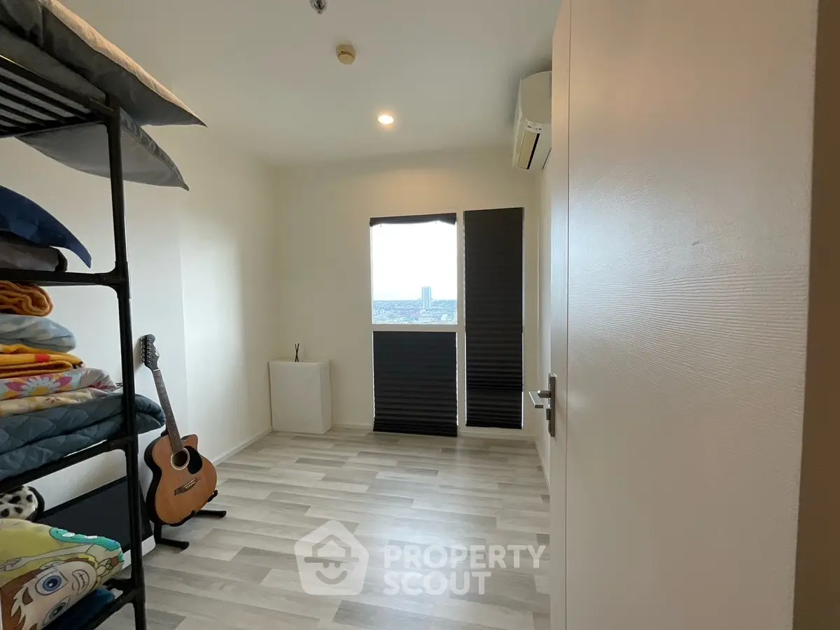 Cozy bedroom with wooden flooring, guitar, and modern decor in a bright apartment.