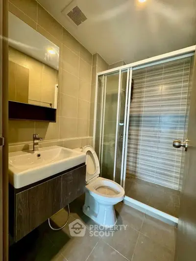 Modern bathroom with sleek fixtures and glass shower enclosure in a contemporary apartment.
