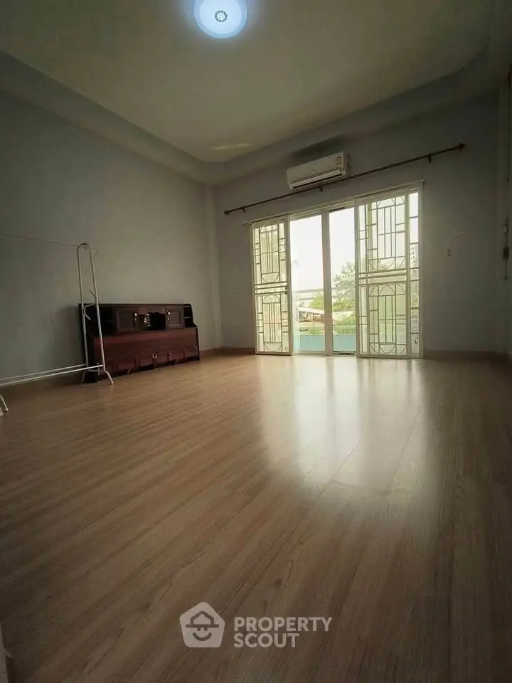 Spacious empty room with wooden flooring and large windows, perfect for customization.