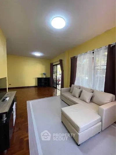 Spacious living room with cozy sofa and natural light, perfect for relaxation.