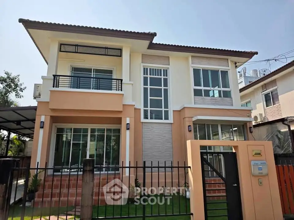 Modern two-story house with large windows and a fenced yard, perfect for family living.
