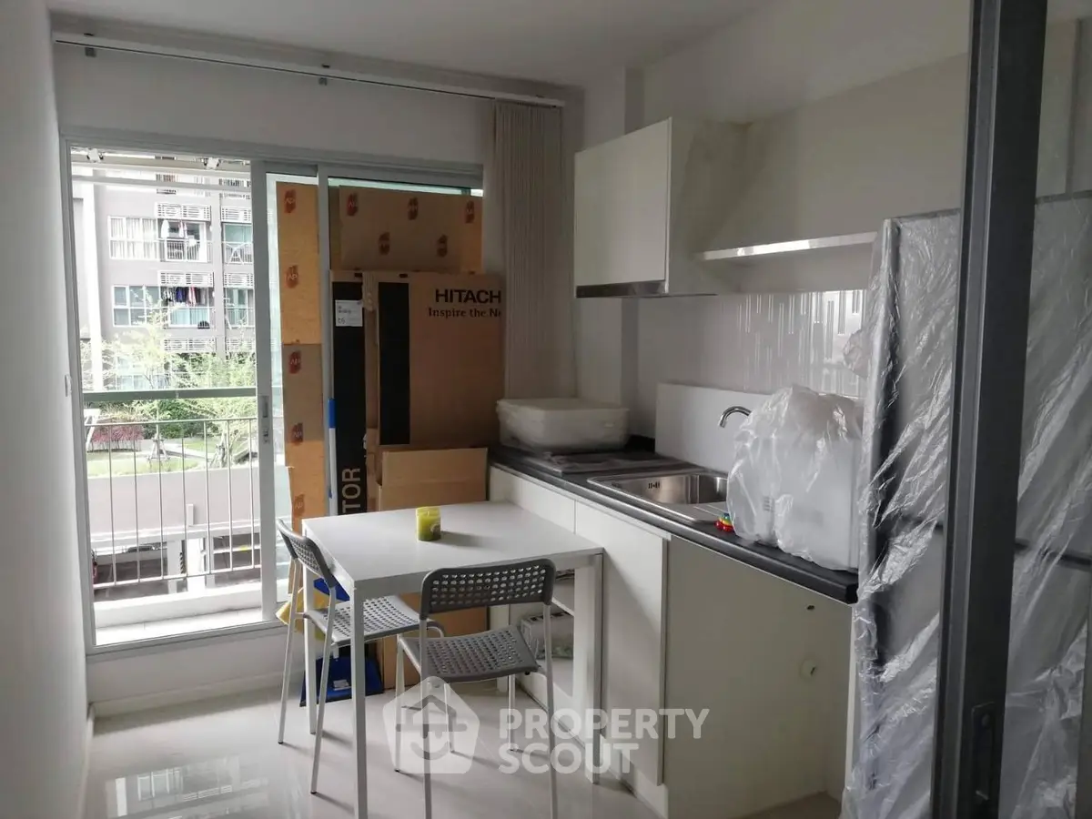 Modern kitchen with balcony view, featuring sleek cabinetry and compact dining area.