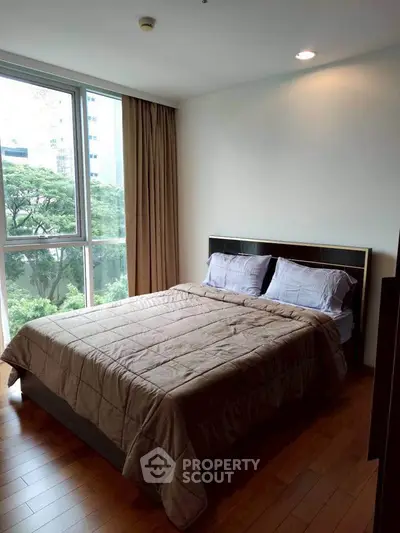 Spacious bedroom with large window offering lush green views, perfect for relaxation and comfort.
