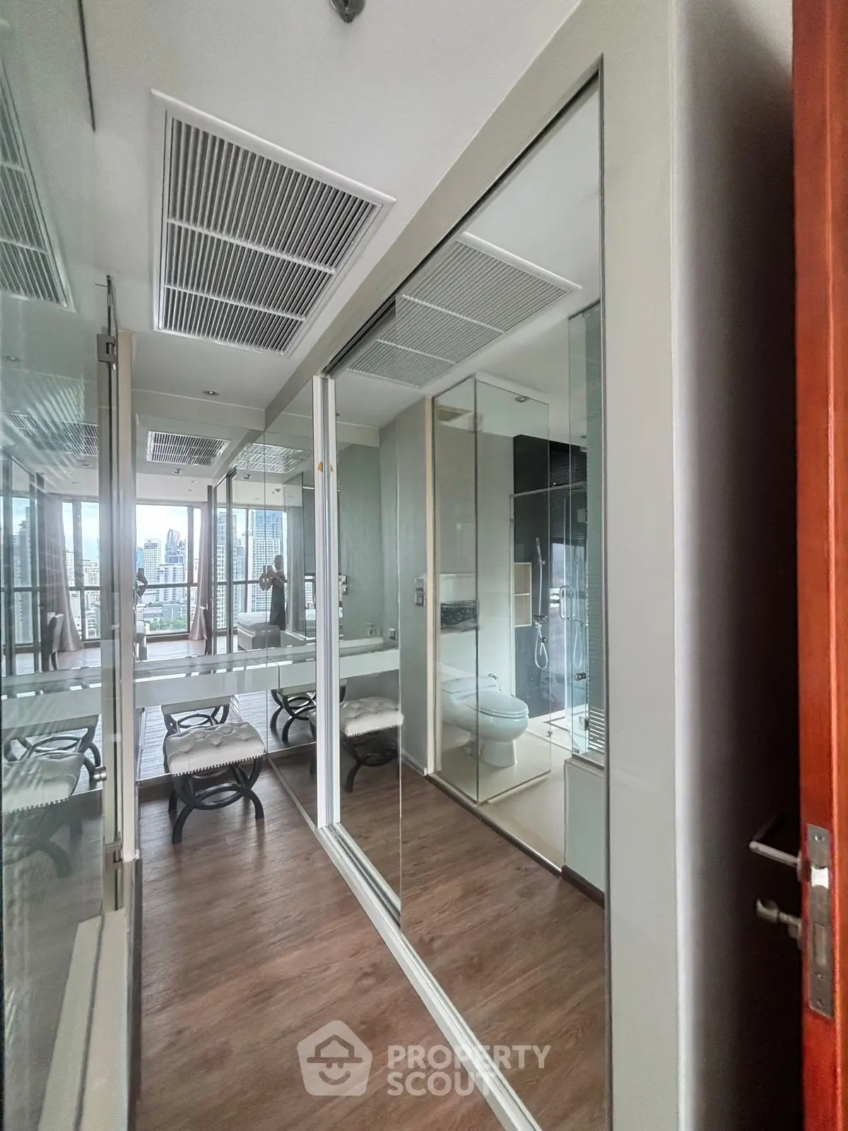Modern bathroom with glass shower and wooden flooring in luxury apartment